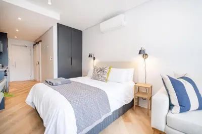 a bedroom with a large white bed and a couch at Paarl 137 - Superior Studio Apartment with AC and Parking in Paarl