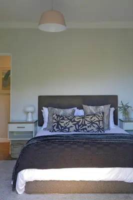 a bedroom with a large bed with a white wall at Seabreeze Retreat in Hermanus