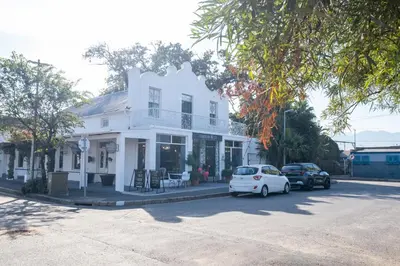 a white house with cars parked in front of it at Paarl Studio 138 - Ultra Modern Apartment with AC and onsite Parking in Paarl