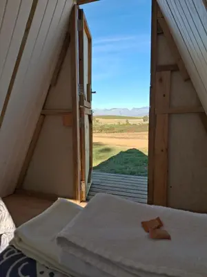 a room with a bed and an open door at Blouporselein guestfarm cabin in Hermon