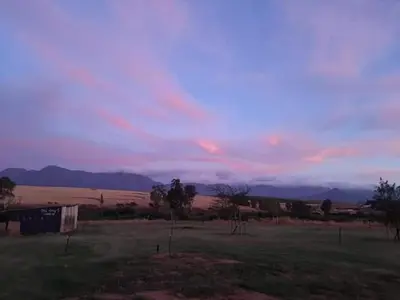 a view of a field with a cloudy sky at Blouporselein guestfarm cabin in Hermon