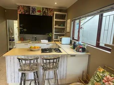 a kitchen with a counter and two bar stools at Winelands Beach Cottage in Gordonʼs Bay