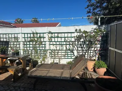 a patio with a bench and a table and a fence at Winelands Beach Cottage in Gordonʼs Bay
