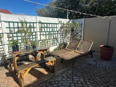 a patio with two benches and a table and chairs at Winelands Beach Cottage in Gordonʼs Bay