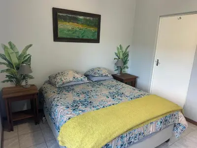 a bedroom with a bed and a painting on the wall at Winelands Beach Cottage in Gordonʼs Bay