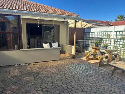 a patio with a table and a picnic table at Winelands Beach Cottage in Gordonʼs Bay