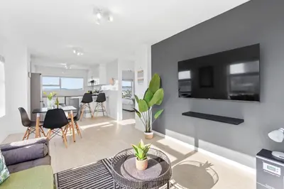 a living room with a couch and a tv on a wall at Ocean View B503 in Cape Town