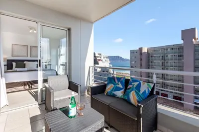 a balcony with a couch and a table and a bedroom at Ocean View B503 in Cape Town