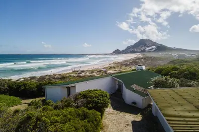 a house on the beach with a view of the ocean at Turtle Drum ON THE BEACH in Bettyʼs Bay