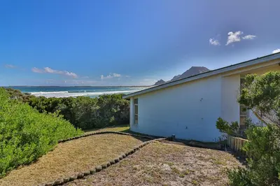 a white house with a view of the ocean at Turtle Drum ON THE BEACH in Bettyʼs Bay