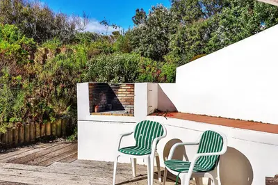 two green and white chairs sitting on a patio at Turtle Drum ON THE BEACH in Bettyʼs Bay
