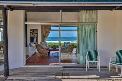 a living room with a view of the ocean at Turtle Drum ON THE BEACH in Bettyʼs Bay