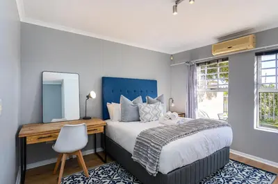 a bedroom with a bed and a desk and a mirror at Century on Lake A45 by CTHA in Cape Town