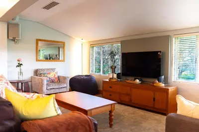 a living room with a flat screen tv on a wooden cabinet at Stellenbosch Farm Stay with Mountain Views & Pool in Stellenbosch