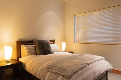 a bedroom with a bed with two lamps and a window at Stellenbosch Farm Stay with Mountain Views & Pool in Stellenbosch