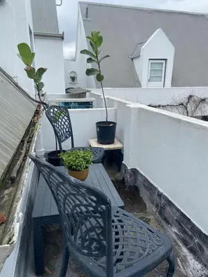 a black chair sitting on a balcony with two plants at Amatoni 44 in Stellenbosch