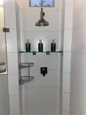 a bathroom with white tile walls and a shelf with candles at Amatoni 44 in Stellenbosch