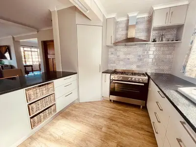 a kitchen with white cabinets and a stove top oven at Voelklip Holiday Home in Hermanus
