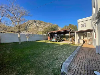 a house with a car parked in a driveway at Voelklip Holiday Home in Hermanus
