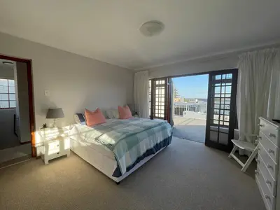 a bedroom with a bed and a balcony at Voelklip Holiday Home in Hermanus