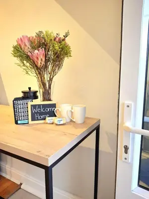 a table with two cups and a vase with flowers at The Harfield Hideaway in Cape Town