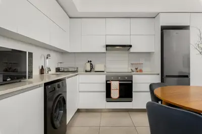 a kitchen with white appliances and a wooden table at Beautiful Beach Break! in Cape Town