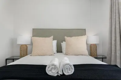 a bedroom with two towels on a bed with two lamps at Beautiful Beach Break! in Cape Town