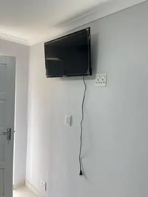 a flat screen tv hanging on a white wall at The Perfect Place in Parow
