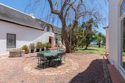 a patio with a table and chairs in front of a building at The Manor at Mont Angelis Estate in Stellenbosch