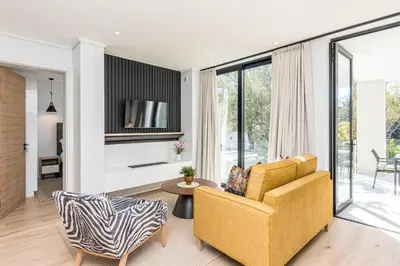 a living room with a yellow couch and a table at Aan de Meul Luxury Apartments in Stellenbosch