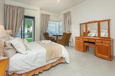 a bedroom with a bed and a desk and a mirror at Iets Nuuts in Hermanus