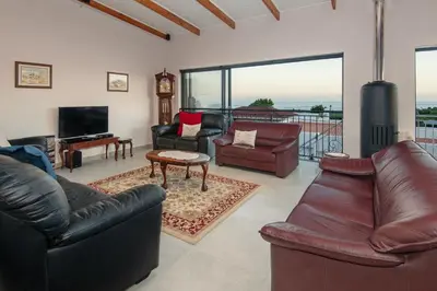 a living room with leather furniture and a flat screen tv at Iets Nuuts in Hermanus