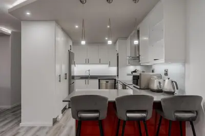 a kitchen with white cabinets and a counter with chairs at 903 Atlantica in Strand