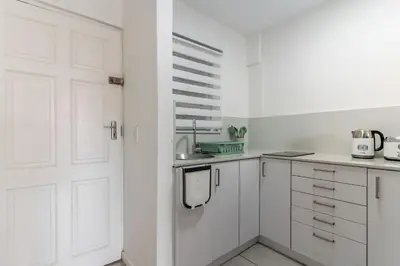 a kitchen with white cabinets and a white door at Manhattan Square 17 in Cape Town