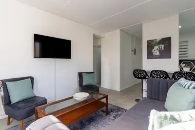 a living room with a couch and chairs and a tv at Manhattan Square 17 in Cape Town
