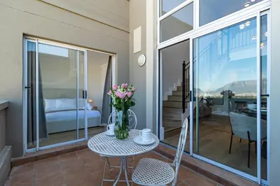 a small table with a vase of flowers on a balcony at 2 Bedroom, Mountain View Penthouse, Century City in Cape Town