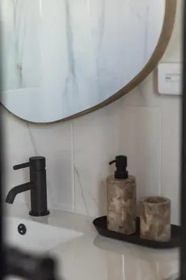 a bathroom sink with a mirror and two soap dispensers at 2 Bedroom, Mountain View Penthouse, Century City in Cape Town