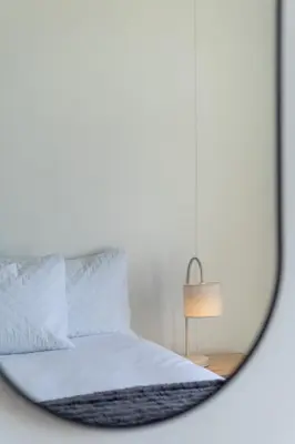 a mirror reflecting a bed with white sheets and a lamp at 2 Bedroom, Mountain View Penthouse, Century City in Cape Town