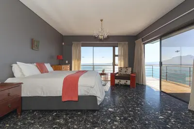 a bedroom with a bed and a view of the ocean at Gordons Bay Villa with Pool in Gordonʼs Bay