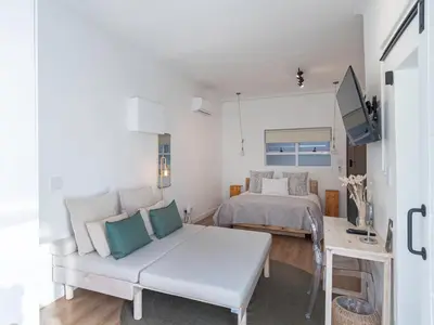 a white living room with a bed and a couch at 107 Dorpstraat Boutique Hotel in Stellenbosch