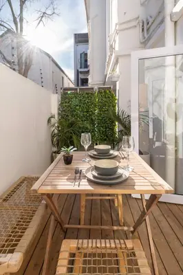 a wooden table with plates and glasses on a balcony at 107 Dorpstraat Boutique Hotel in Stellenbosch