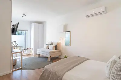 a white bedroom with a bed and a chair at 107 Dorpstraat Boutique Hotel in Stellenbosch