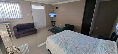 a room with a bed and chairs and a television at Murray Guest Suite in Goodwood