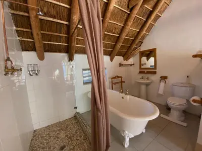 a bathroom with a tub and a toilet and a sink at The Welgemoed Guest House in Bellville