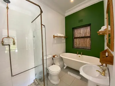 a bathroom with a tub and a toilet and a sink at The Welgemoed Guest House in Bellville