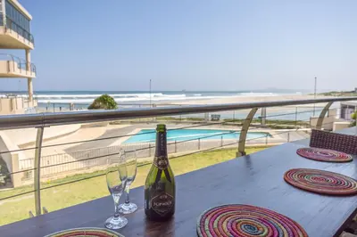 a bottle of wine and glasses on a table on a balcony at The Lagoon Beachfront Apartment in Cape Town