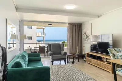 a living room with a green couch and a television at The Lagoon Beachfront Apartment in Cape Town
