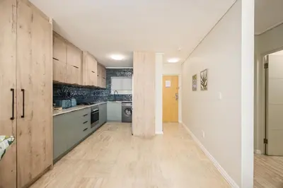 a large kitchen with wooden cabinets and a hallway at The Lagoon Beachfront Apartment in Cape Town