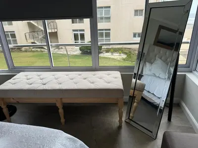 a mirror and a bench in a room with a window at The Lagoon Beachfront Apartment in Cape Town