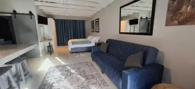 a living room with a blue couch and a bed at Kiewiets Nest in Victory Hill